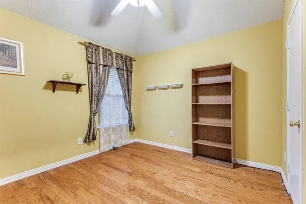 a view of an empty room with a window and wooden floor