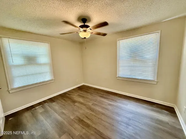a view of an empty room with a window and wooden floor