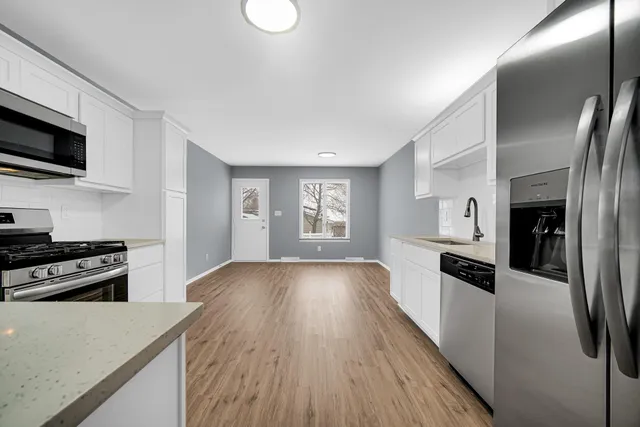 a kitchen with stainless steel appliances granite countertop a refrigerator a stove top oven a sink dishwasher and wooden floor