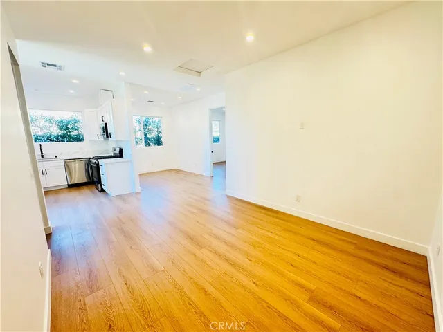 a view of a big room with wooden floor and windows