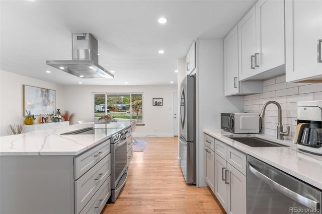 a kitchen with kitchen island granite countertop a sink stainless steel appliances and cabinets