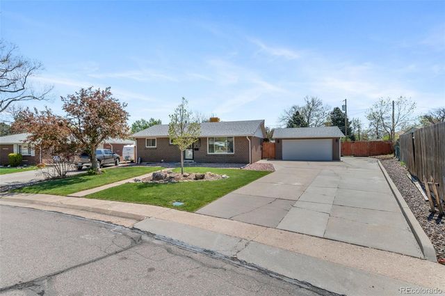a front view of house with yard and trees in the background