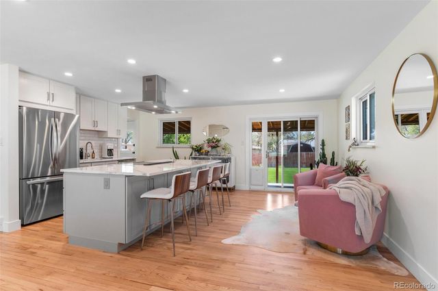 a living room with stainless steel appliances kitchen island granite countertop furniture wooden floor and a view of kitchen