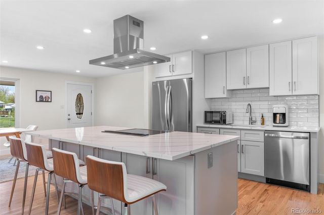 a kitchen with stainless steel appliances a kitchen island hardwood floor sink and stove