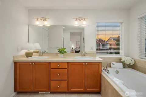 a spacious bathroom with a double vanity sink a large mirror a bathtub and shower
