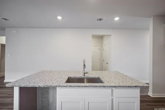 a kitchen with a granite countertop sink and white cabinets