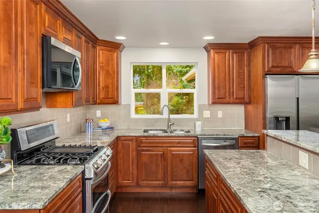 a kitchen with stainless steel appliances granite countertop a stove a sink and a microwave