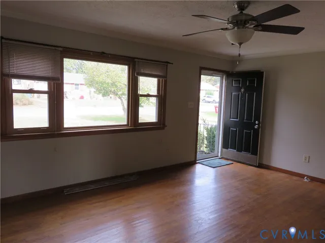 an empty room with wooden floor and windows