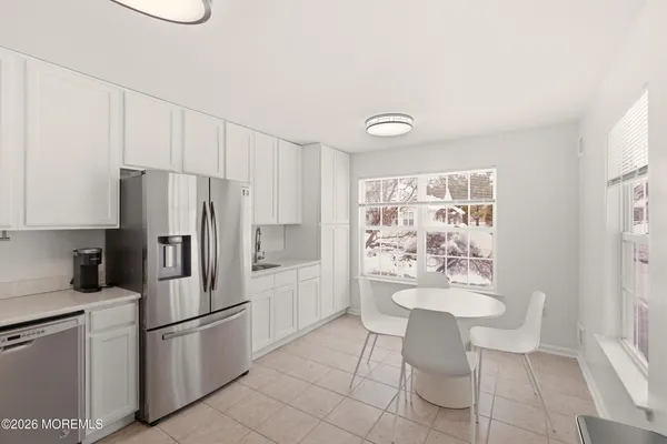a kitchen with a refrigerator and white cabinets