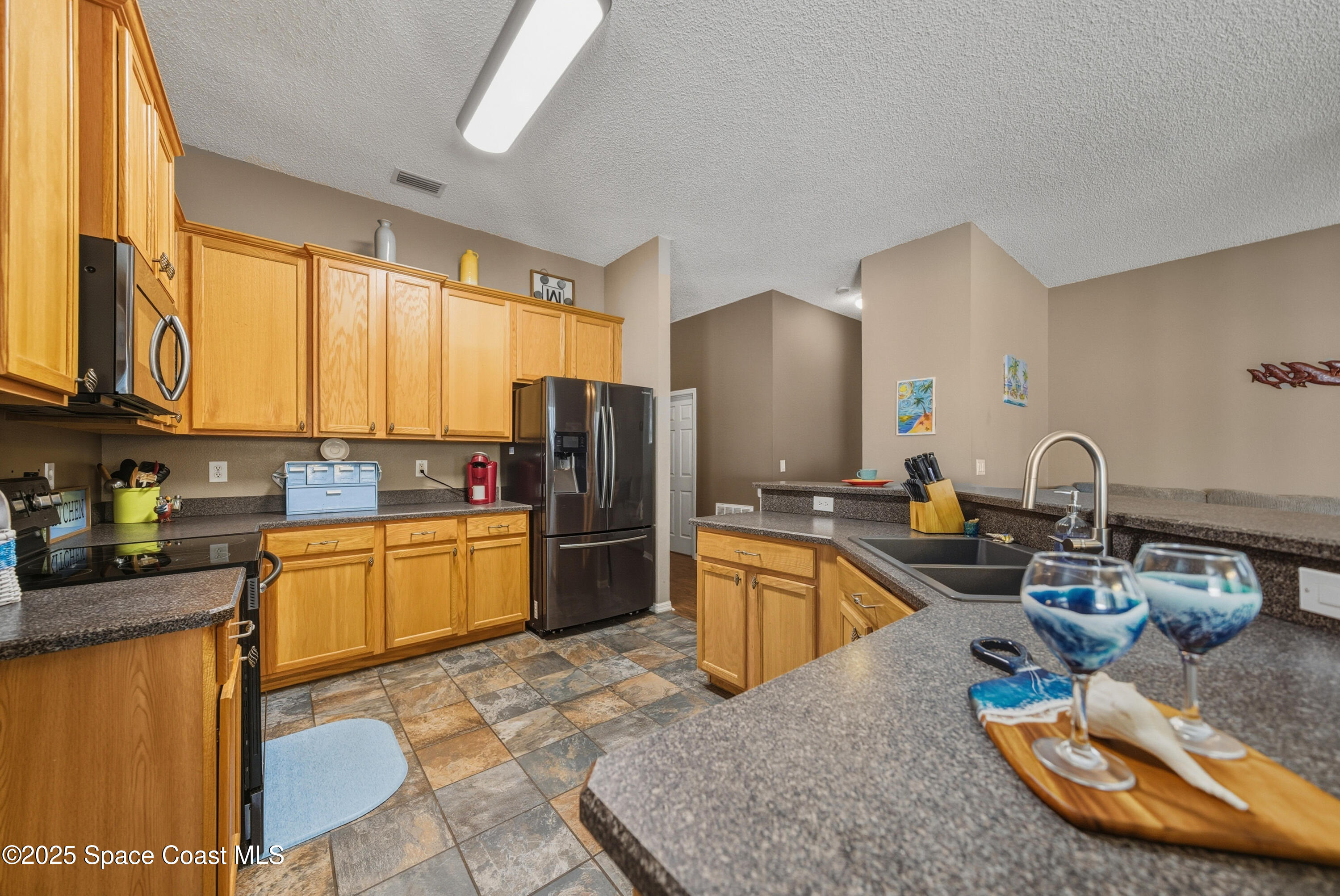 7368 Crepe Myrtle Court Cocoa, FL 32927 - Photo 13 of 50 a kitchen with stainless steel appliances granite countertop a sink a stove and refrigerator