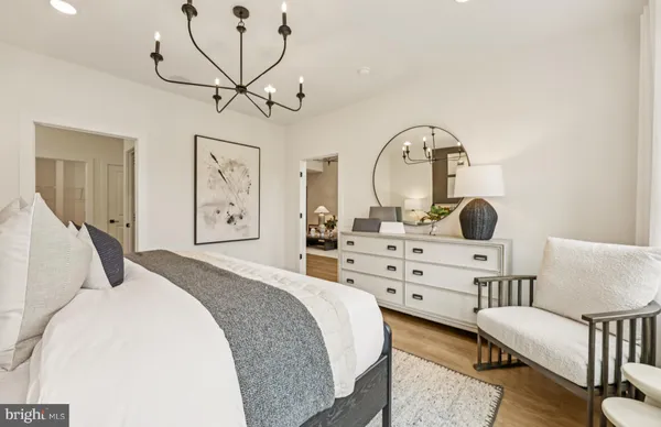 a bedroom with a bed a chandelier and dresser