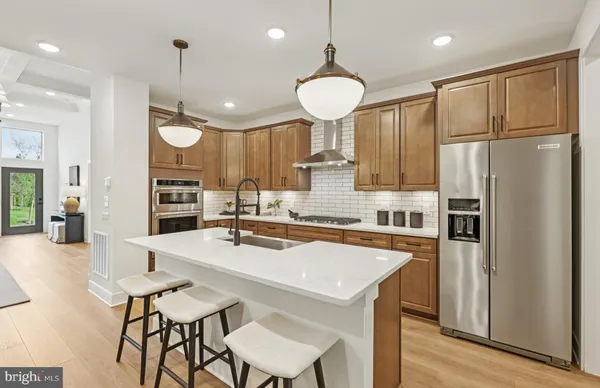 a kitchen with stainless steel appliances a refrigerator a sink cabinets and wooden floor