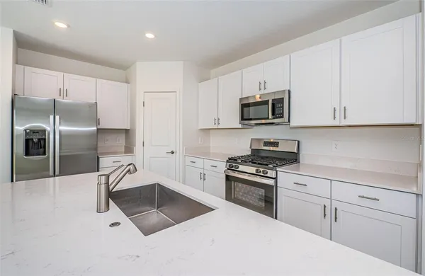 a kitchen with granite countertop a refrigerator sink and white cabinets