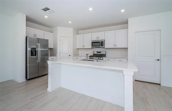 a kitchen with kitchen island a refrigerator sink and cabinets