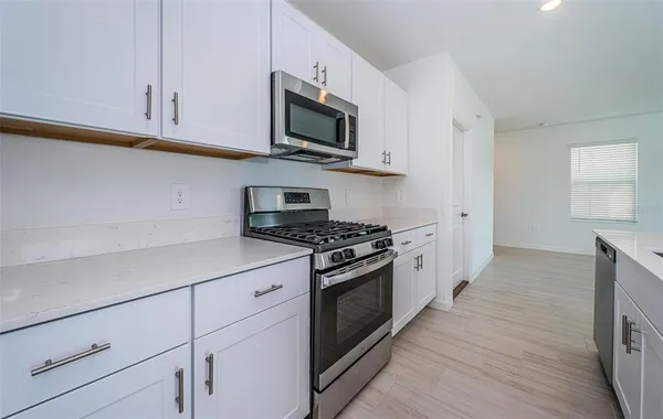 a kitchen with stainless steel appliances granite countertop a stove a sink and a microwave