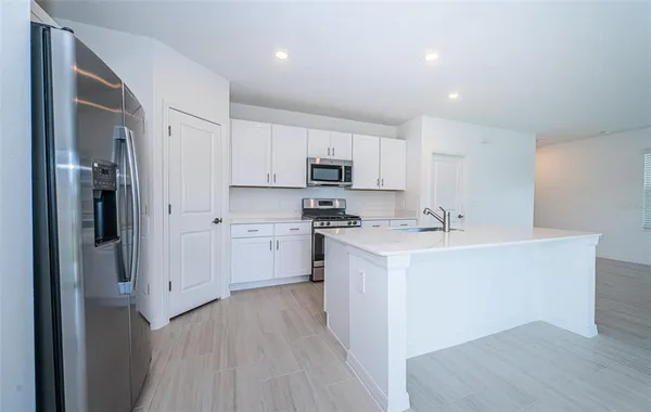 a kitchen with stainless steel appliances a refrigerator sink and white cabinets