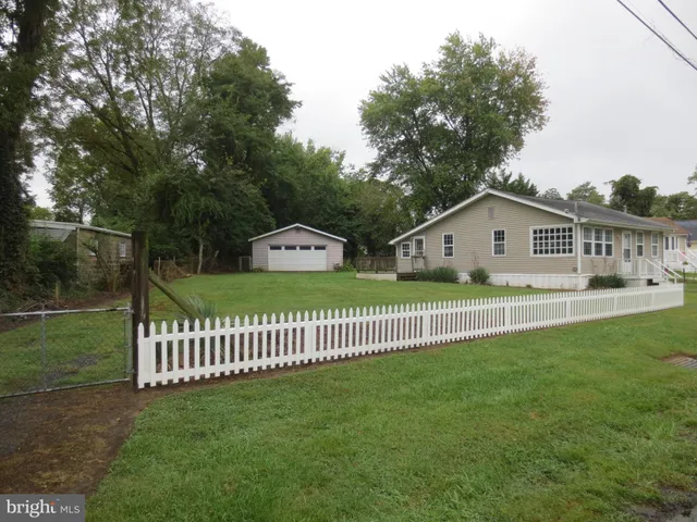 a view of a white house with a small yard and a garden