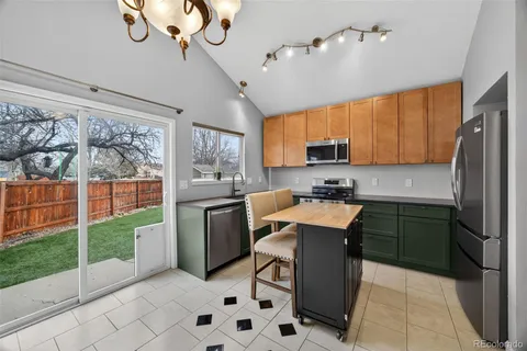 a kitchen with a refrigerator a sink dishwasher a dining table and chairs with wooden floor
