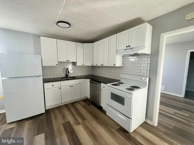a kitchen with granite countertop white cabinets and white appliances