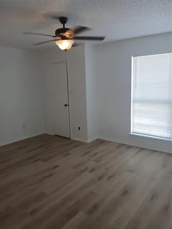 a view of a room with a chandelier fan and wooden floor
