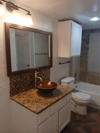 a bathroom with a granite countertop sink a toilet and a mirror