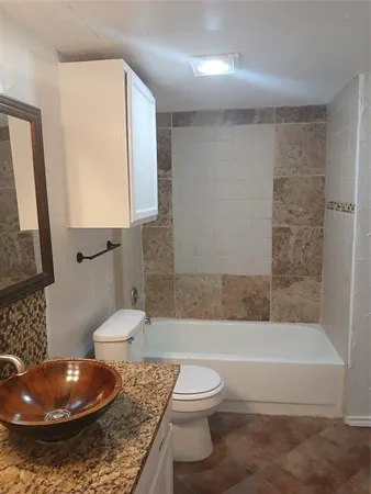 a bathroom with a granite countertop toilet and a bathtub