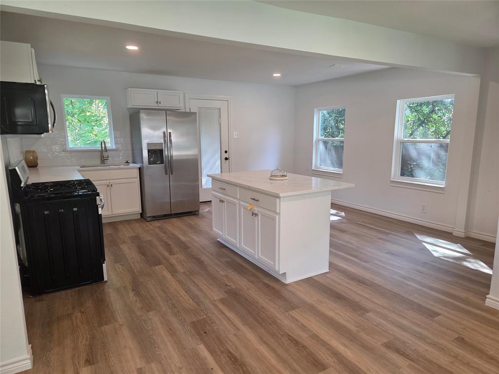 2108 Blake Avenue Dallas, TX 75228 - Photo 3 of 13 Modern kitchen island with white shaker cabinetry and a light-toned countertop