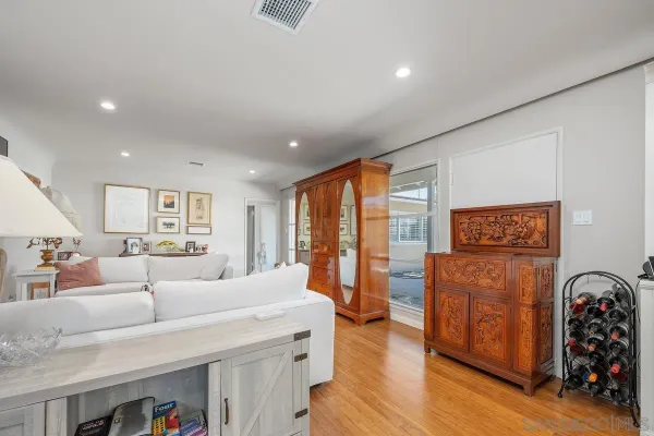 a large living room with stainless steel appliances wooden floor and a large window
