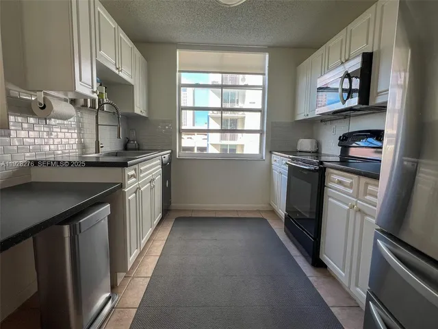 a kitchen with stainless steel appliances granite countertop a stove a sink dishwasher and a refrigerator