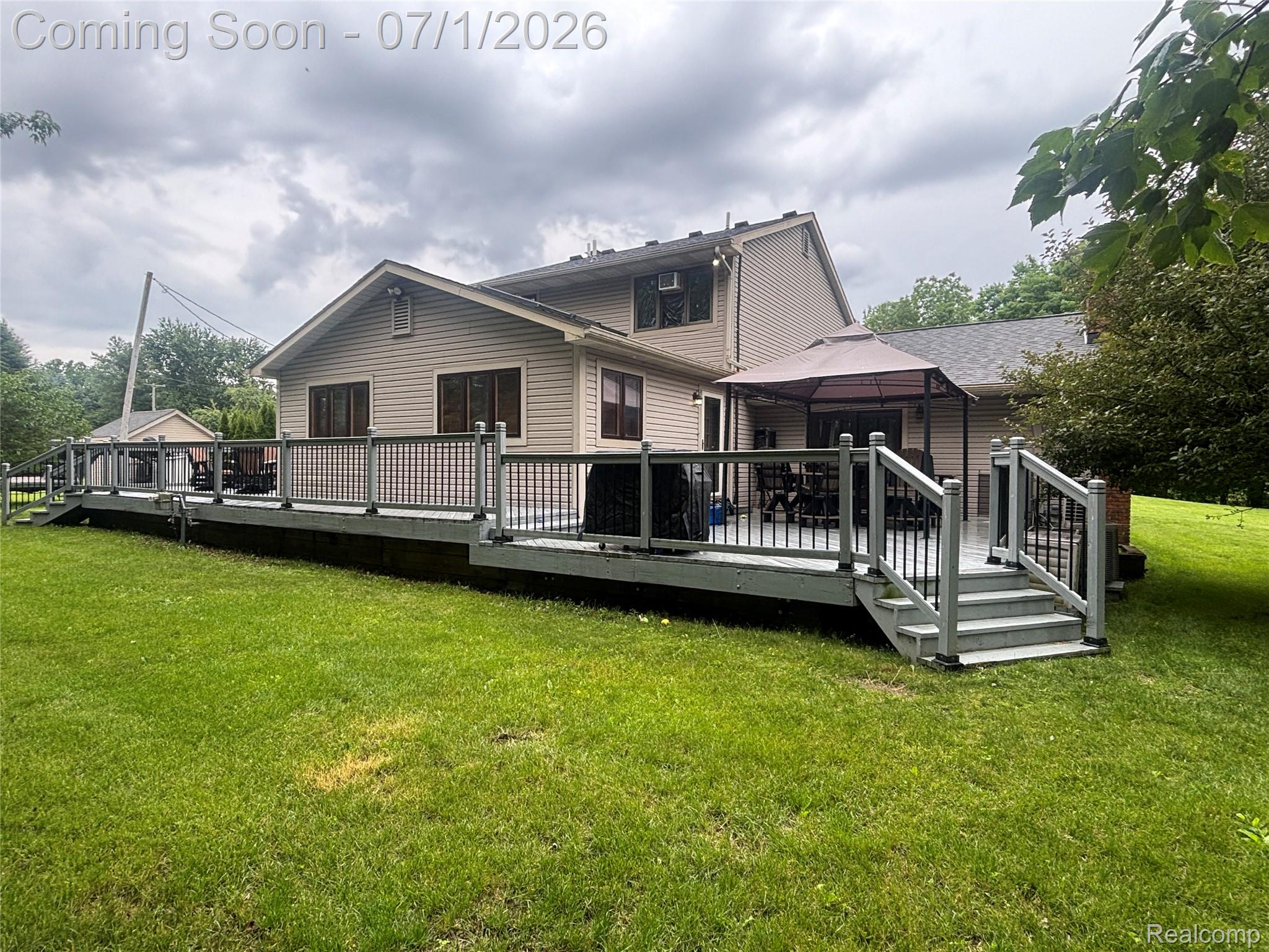 9844 Pine Knob Road Clarkston, MI 48348 - Photo 4 of 15 Expansive rear deck featuring a light gray finish, black metal balusters, and a built-in staircase