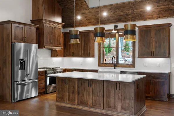 a kitchen with stainless steel appliances granite countertop a refrigerator a sink a stove and a wooden floors