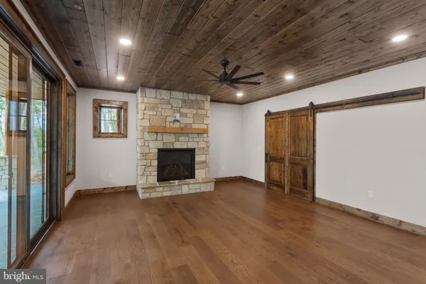 a view of an empty room with wooden floor a fireplace and a window