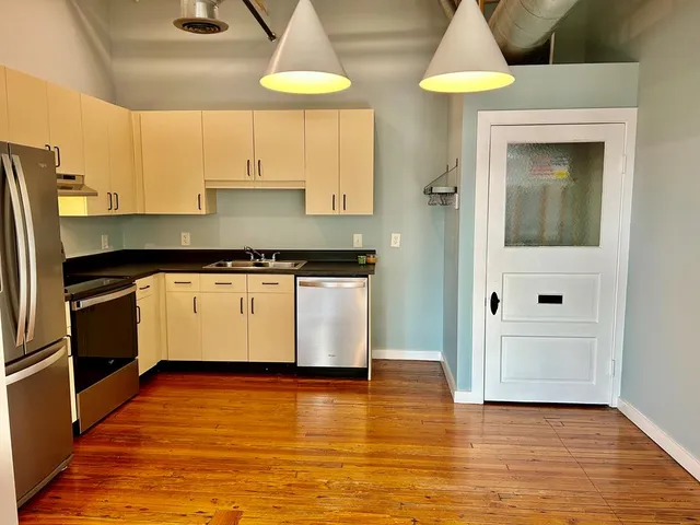 a kitchen with stainless steel appliances granite countertop a refrigerator a stove a sink and white cabinets