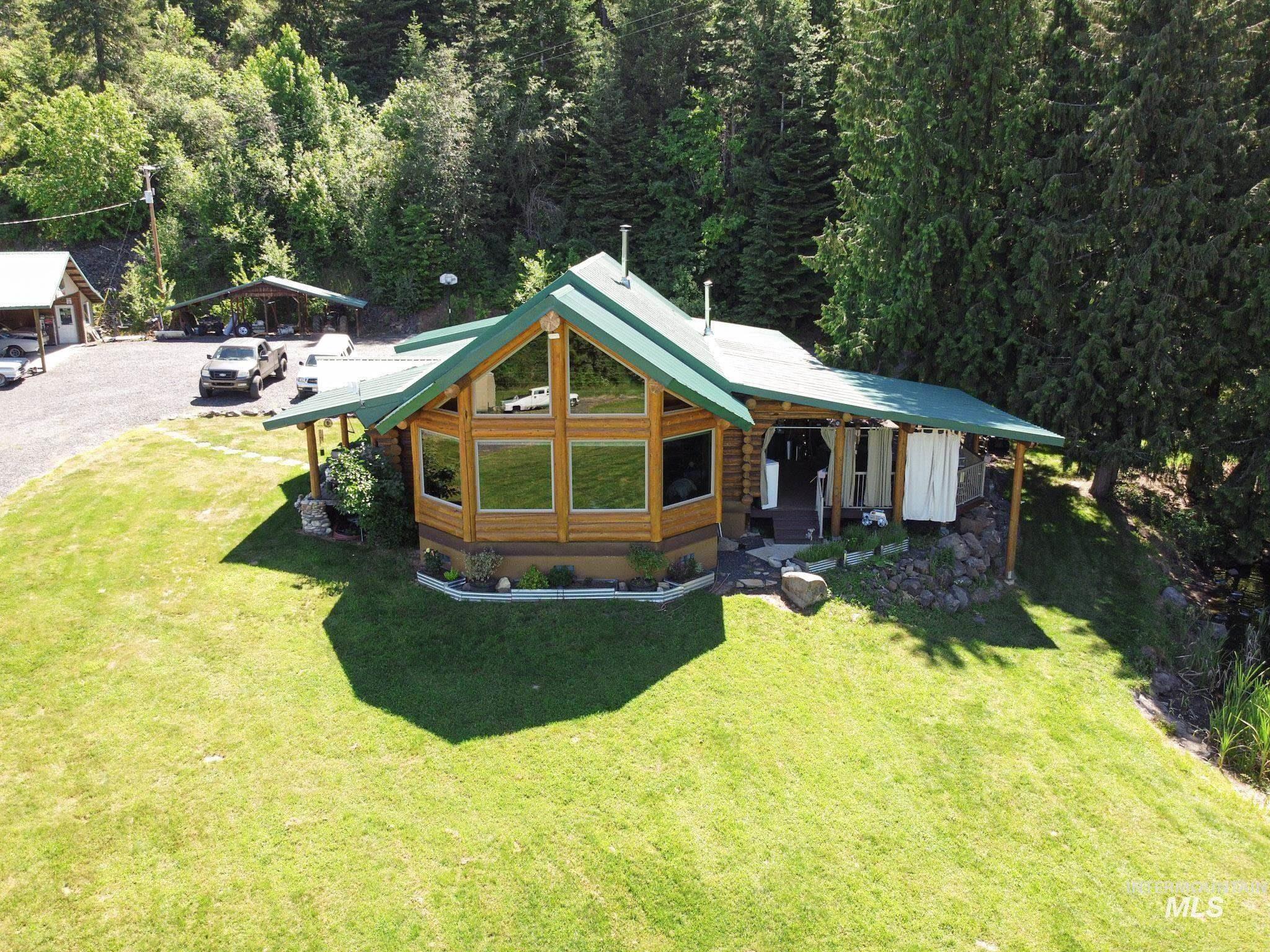 112 Three Forks Road Kamiah, ID 83536 - Photo 2 of 45 View of front of house with log exterior, a detached carport, a front lawn, and a metal roof