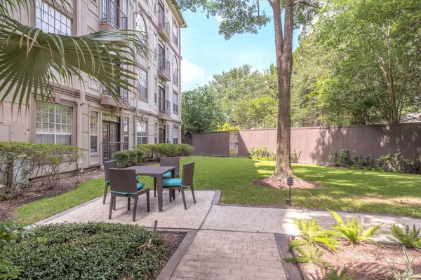 a view of a backyard with table and chairs potted plants and palm trees