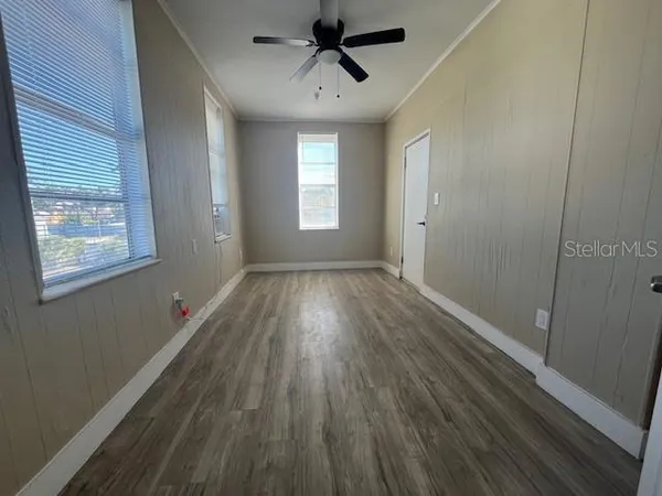 a view of empty room with wooden floor and fan