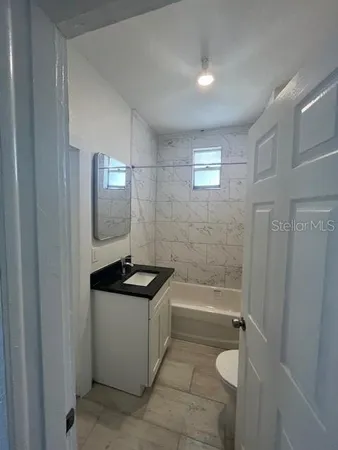a bathroom with a granite countertop sink a toilet a mirror and bathtub