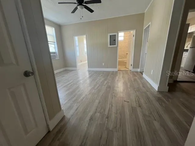 a view of a hallway with wooden floor and a chandelier fan