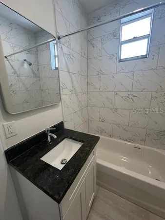 a bathroom with a granite countertop sink a toilet and bathtub
