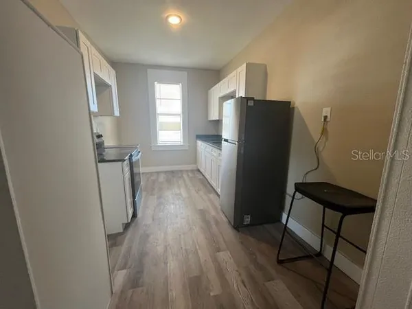 a kitchen with a refrigerator and wooden floor