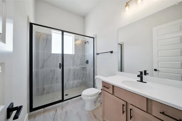 a bathroom with a shower sink vanity mirror and toilet