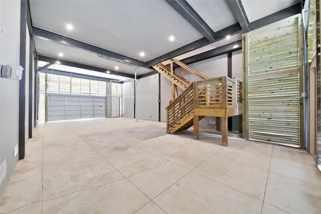 a view of an empty room with wooden floor and windows