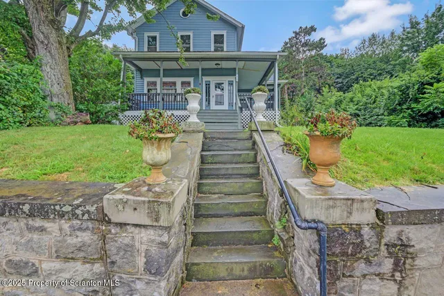 a view of a house with a big yard plants and large trees