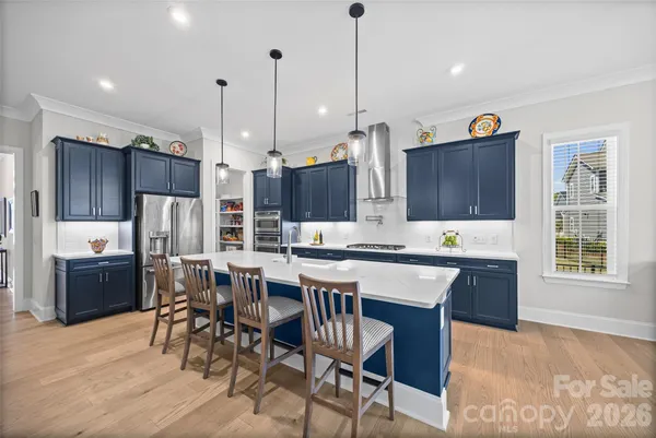 a kitchen with stainless steel appliances granite countertop a stove top oven a refrigerator a sink and chairs