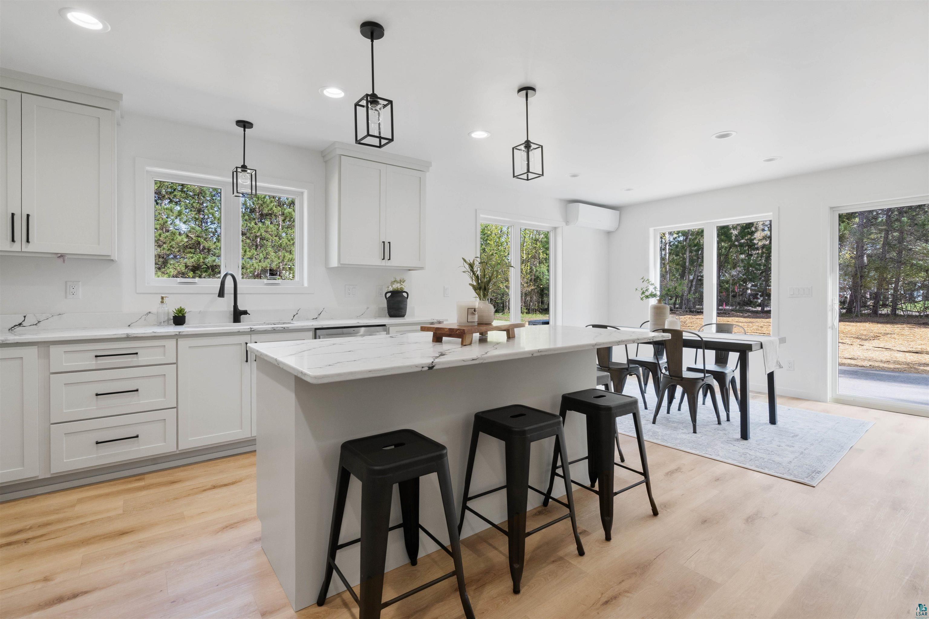 1386 Stephen Road Cloquet, MN 55720 - Photo 13 of 25 Bright kitchen space featuring white shaker cabinetry, light wood-finish flooring, and a central island with a white countertop