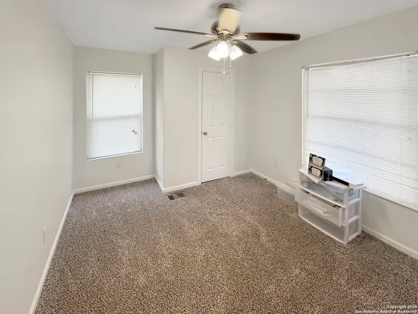an empty room with windows and fan