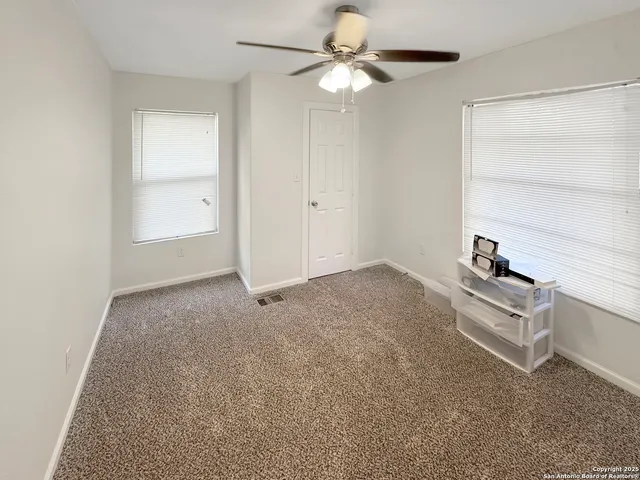 an empty room with windows and fan
