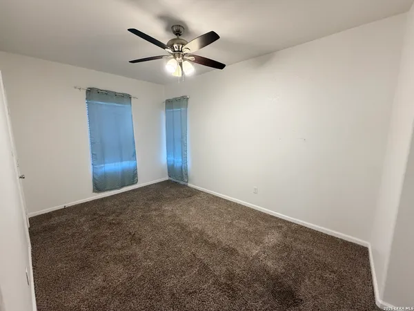 an empty room with a chandelier fan and closet
