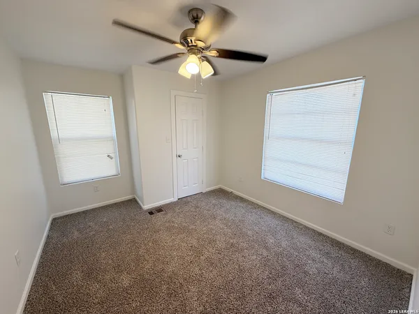 an empty room with a chandelier fan and windows