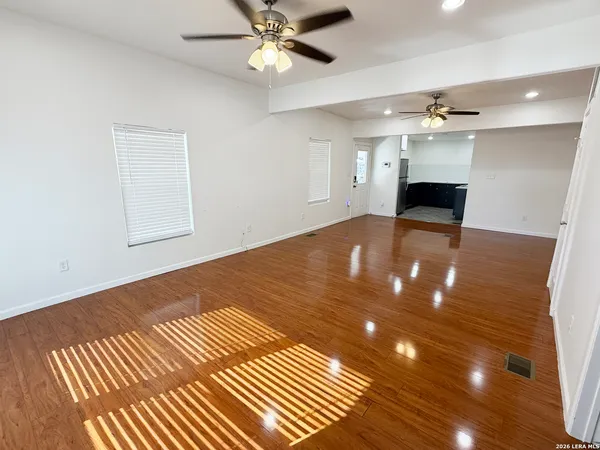 a view of an empty room with a chandelier fan and wooden floor
